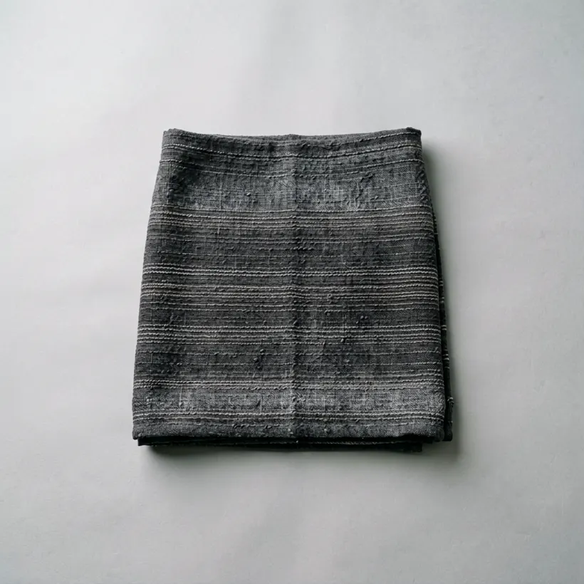 A folded wrap skirt length in charcoal and undyed cotton with fine horizontal banding