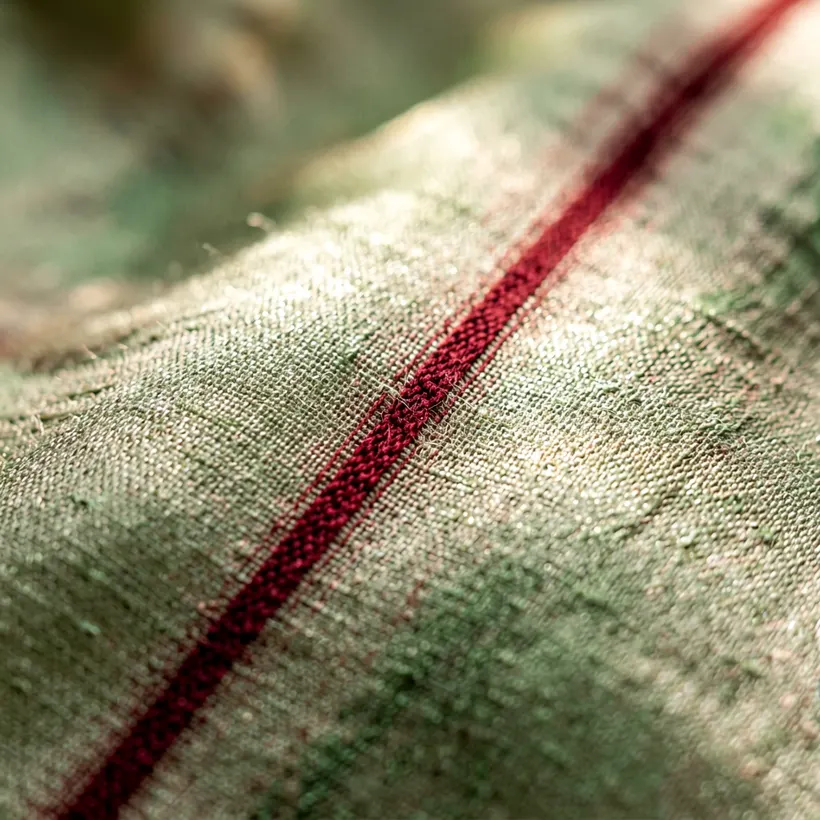 Extreme macro of undyed eri silk weave with a fine madder red stripe running through it
